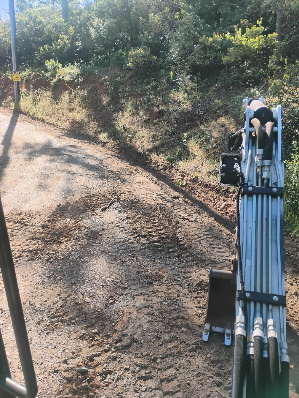 Excavator grading driveway in Mariposa CA for drainage and access