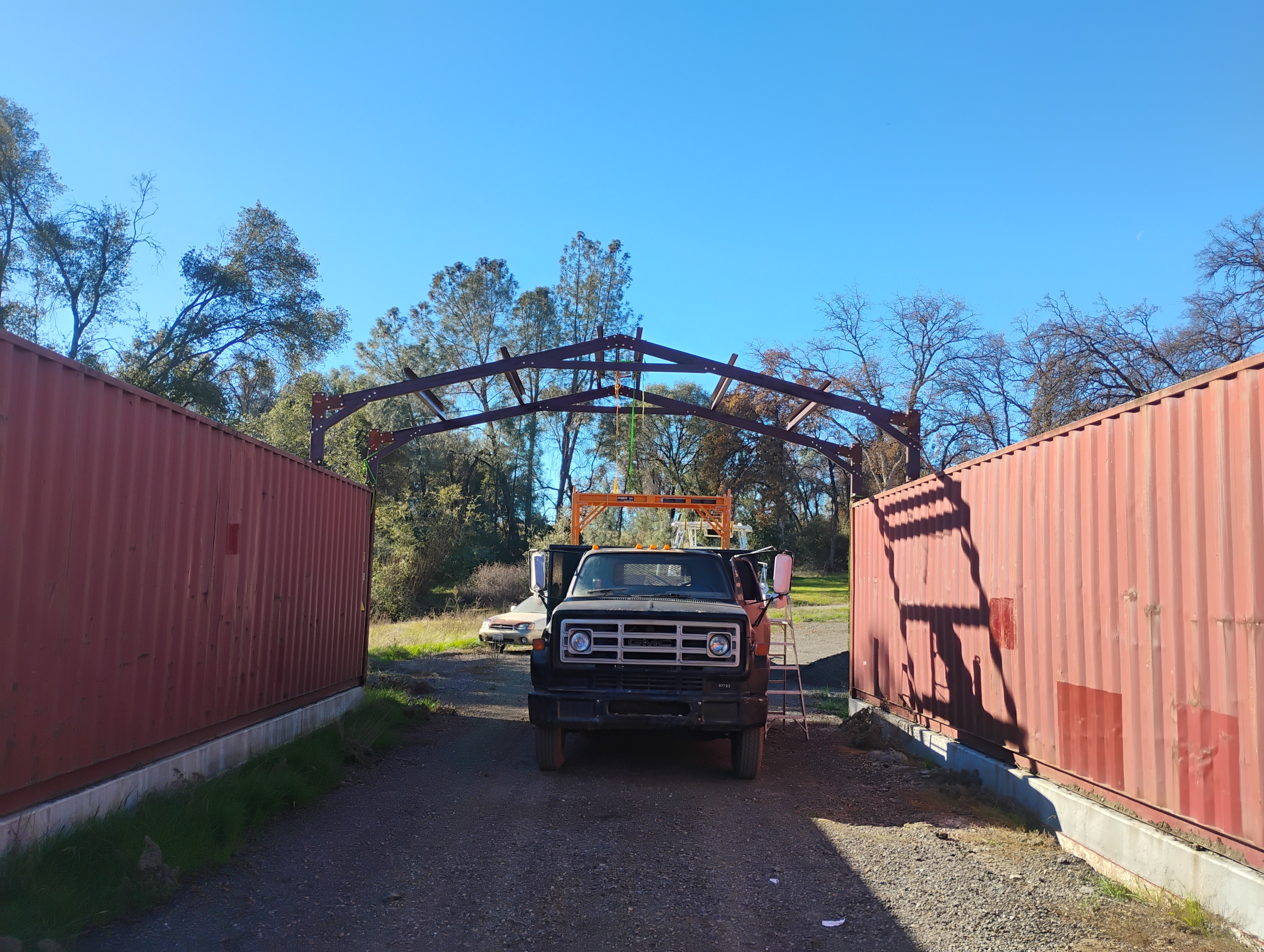 Steel building installation between shipping containers in Mariposa CA